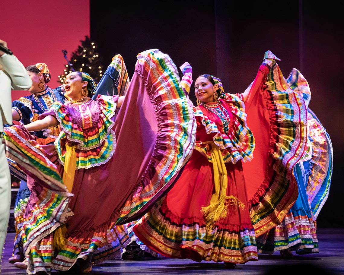 A group of performers in colorful outfits dancing.
