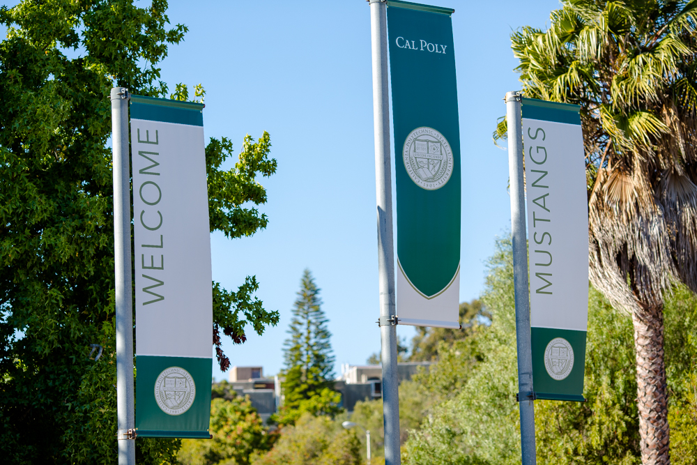 Three Cal Poly flags displaying Welcome Cal Poly Mustangs
