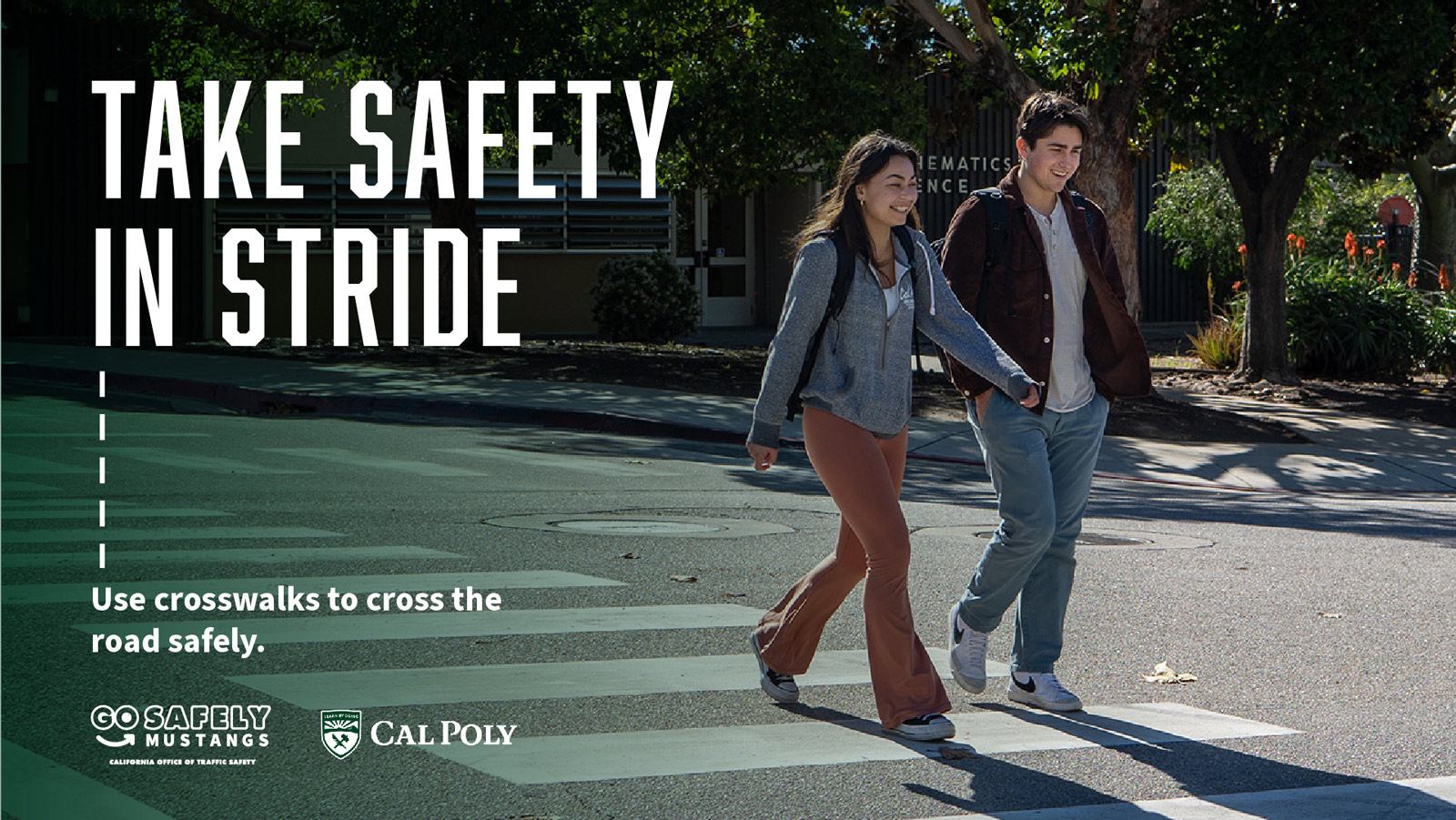 Two students smiling as they cross at a marked crosswalk. Text reads 'Take safety in stride'.